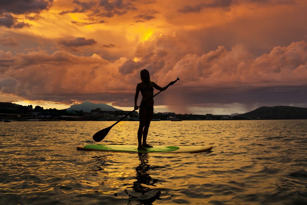 Silhouette of a girl on Stand Up Paddle Board on the background